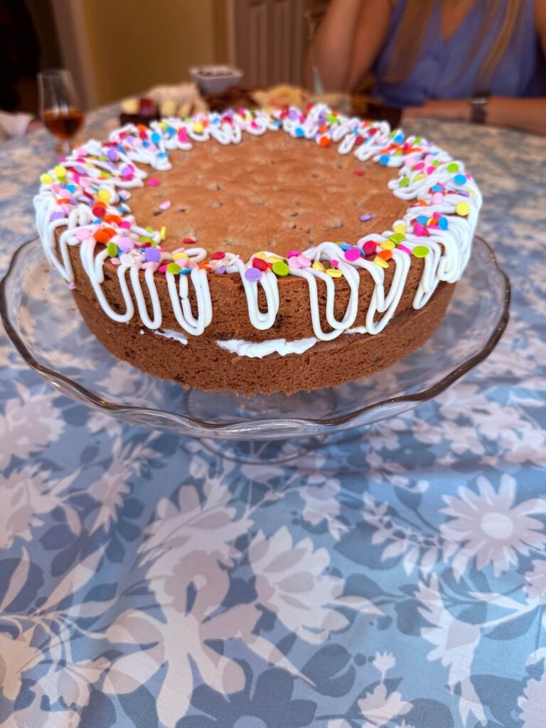 Layered chocolate chip cookie cake on a glass cake stand