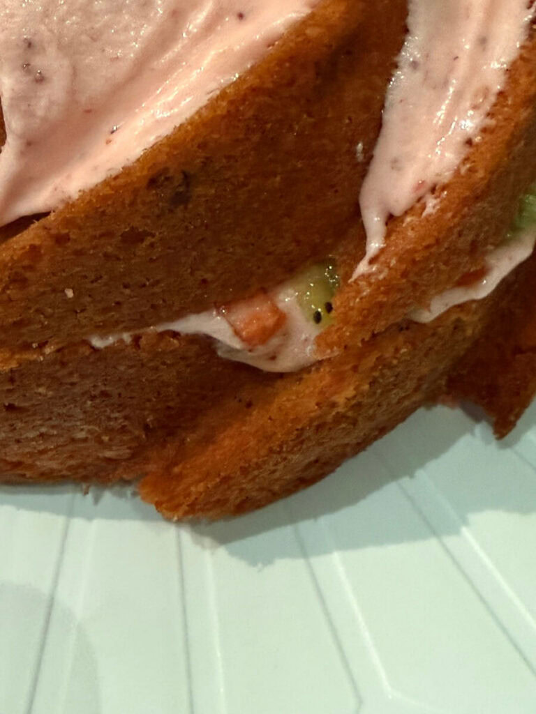 close up of a strawberry cake layers with strawberry and kiwi filling between the layers.